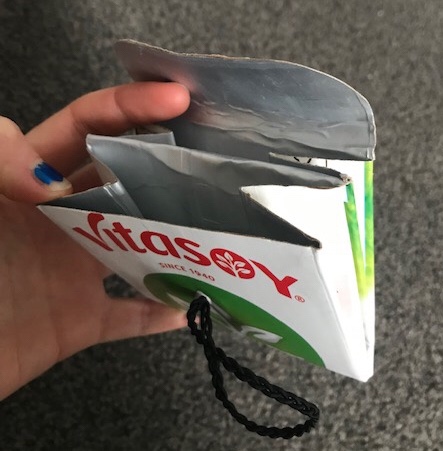 Upcycled rice milk tetrapak purse: folded in half to make a pouch, secured with plaited black elastic